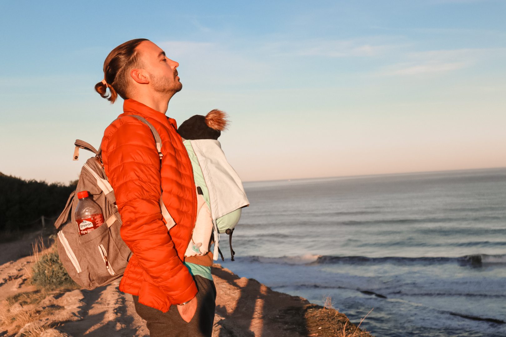 Viajar con bebés - bebé en porteo en pasisaje norte de españa